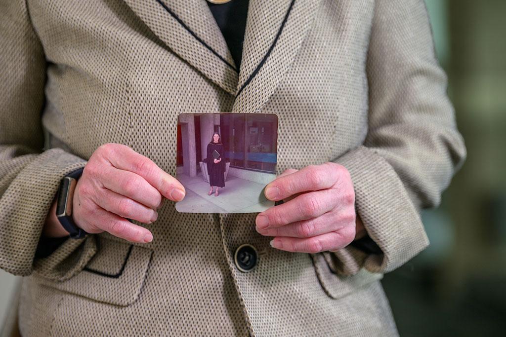 Eileen C. holding a picture of herself at her 1975 graduation